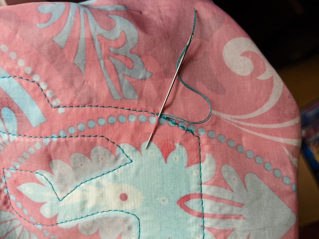 Embedding end of thread between applique and fabric